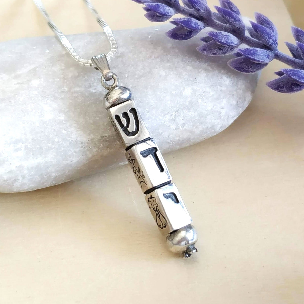 A silver mezuzah pendant necklace with Hebrew letters שדי, kinetic 3D design